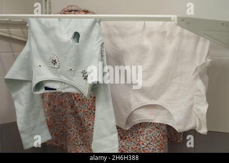 Am Trockner hängende Kleidung, Babykleidung. Stockfoto