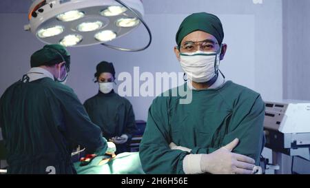 Chirurg Arzt posiert mit gekreuzten Armen, Ärztliche chirurgische Ärzteteam, das OP-Patient im Operationssaal mit Elektrokauterausrüstung für c Stockfoto
