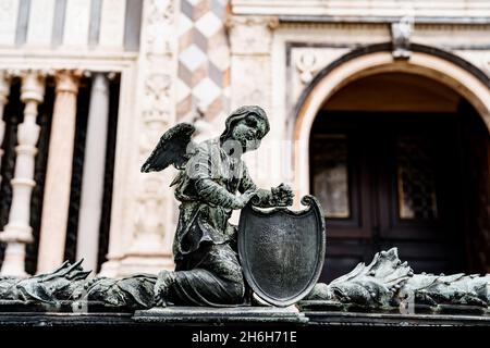 Statue eines Engels mit einem Schild in der Nähe des Eingangs zur Colleoni-Kapelle. Bergamo, Italien Stockfoto