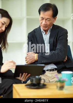 Erfolgreicher Geschäftsmann mittleren Alters, der ein Treffen mit seinem Assistenten im Büro hat. Stockfoto
