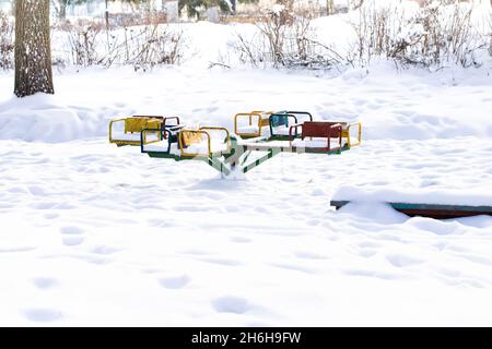 Kinderkarussell nach einem Schneefall ohne Kinder im Park. Russland. Stockfoto