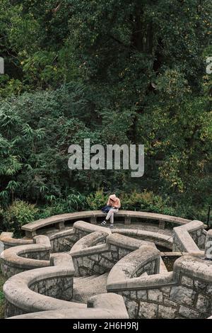 Ein junger Mensch liest im geometrisch gemusterten italienischen Garten des Maymont Estate, Richmond, VA. Stockfoto