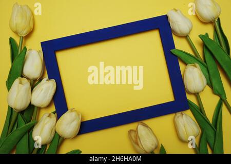 Leer von Fotorahmen und Tulpenblüten Blumenstrauß auf gelbem Hintergrund Stockfoto