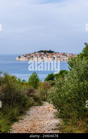 Ein Wanderweg führt zur Küste des Adriatischen Ozeans mit idyllischem kroatischen Fischerdorf im Hintergrund Stockfoto