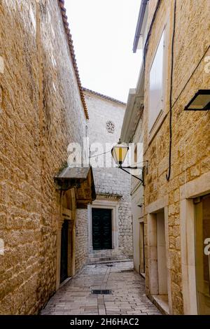 Eine schmale Gasse mit Kopfsteinpflasterstraße und alten Gebäuden im historischen Stadtzentrum von Trogir Stockfoto