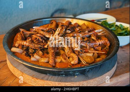 Krake und Garnelen mit Kartoffeln in Metallpfanne verzehrfertig Stockfoto