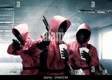 Gruppe von Kriminellen in rosa Uniform und einer versteckten Maske mit der Schrotflinte nach dem Raub des Gebäudes Stockfoto