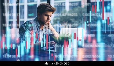Junger Mann, der im modernen Büro arbeitet.Technische Kursgrafik und Indikator, roter und grüner Kerzenchart und Aktienhandel Computerbildschirm Hintergrund. Stockfoto