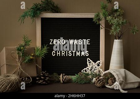 Zero Waste Weihnachtskonzept. Natürliche Materialien, Holz, Papier, Verpackungen, Tannenzweige Kegel Nüsse. Rahmen mit einer Inschrift. Grußkarte im Öko-Stil Stockfoto