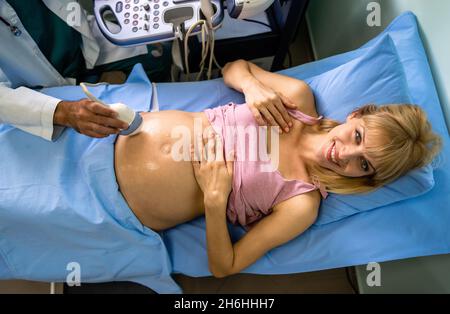 Geburtshelferin untersucht den Bauch einer Schwangeren durch Ultraschalluntersuchung im Krankenhaus. Stockfoto