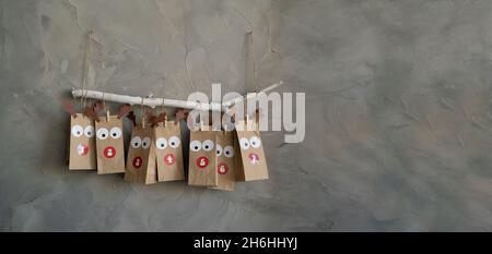 Handgefertigter Adventskalender mit Papiertüten und Aufklebern an der Wand, weihnachts-Retro-Hintergrund, Neujahr-Überraschung. Stockfoto