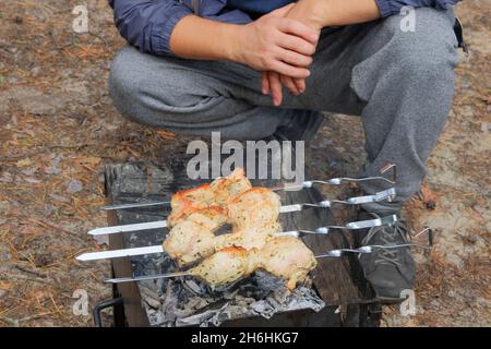 Shish Kebab wird im Freien im Wald gebraten. Fleischbraten auf dem Grill im Freien. Gebratene Hähnchenfleischspieße auf Kohlen. Stockfoto