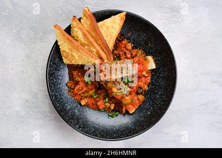 Draufsicht auf gebratenen Zander, serviert mit gedämpfter Tomate, Zwiebel und Olivensoße auf einem Teller Stockfoto