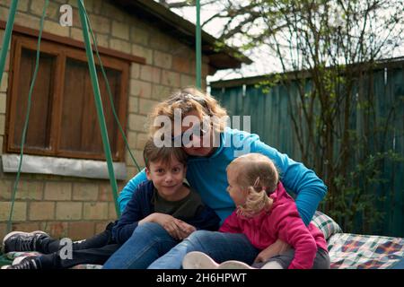 Großmutter und ihre zwei Enkelkinder, die Spaß auf einer Schaukel haben, Enkel und Enkelin lieben ihre Oma. Entspannende Outdors in Oma Landschaft Hou Stockfoto