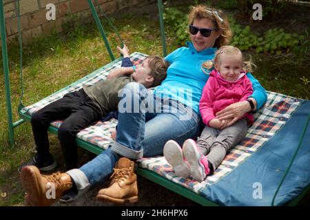 Großmutter und ihre zwei Enkelkinder, die Spaß auf einer Schaukel haben, Enkel und Enkelin lieben ihre Oma. Entspannende Outdors in Oma Landschaft Hou Stockfoto