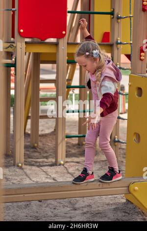Kinder spielen auf dem Spielplatz. Glücklich lachende Mädchen haben Spaß schwingen und klettern. Aktivitäten im Freien Stockfoto