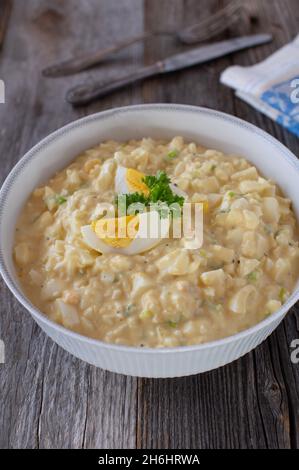 Schüssel mit frischem und hausgemachtem traditionellen Eiersalat isoliert auf Holztisch. Vertikales Bild Stockfoto