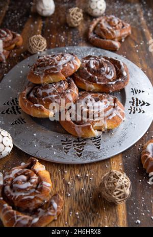 Frische und hausgemachte Zimtschnecken für die weihnachtszeit. Serviert auf einem silbernen Teller auf einem Holztisch. Vertikales Bild Stockfoto