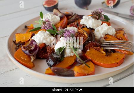 Vegetarisches Fitnessmenü mit gebratenem und karamellisiertem Pumpkin, Feigen und roten Zwiebeln, serviert mit Quark auf einem Teller Stockfoto