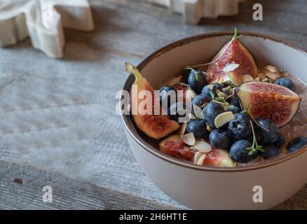 Fitness-Frühstückschale mit einem Brei aus Schokoladenmolkenprotein, gerösteten Mandeln, Feigen und frischen Heidelbeeren. Stockfoto