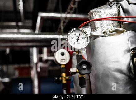 Barometer an Druckleitungen, Technikraum mit Wärme- und Wasserverteilung Stockfoto