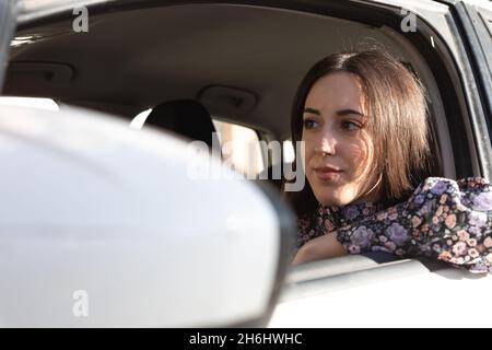 Selbstbewusste und glückliche junge Brünette Dame, die in einem Auto fährt Stockfoto
