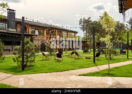 Pavillon mit hölzernen Nischen im ländlichen Golfclub der Vororte. Der Platz für Freizeit Longe, Liegestühle. Arten auf dem Spielplatz Bouncing und Springen auf dem t Stockfoto