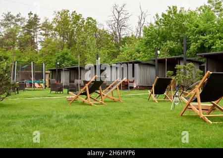 Pavillon mit hölzernen Nischen im ländlichen Golfclub der Vororte. Der Platz für Freizeit Longe, Liegestühle. Arten auf dem Spielplatz Bouncing und Springen auf dem t Stockfoto