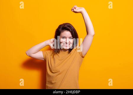 Fröhliche Person, die Tanz macht, bewegt sich vor der Kamera, Spaß mit Musik im Studio. Fröhliche Frau, die die Kamera anschaut und auf Klängen tanzt. Aktiver Erwachsener mit flippiger Leistung. Stockfoto