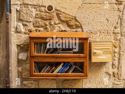 Ein Holzschrank mit einer Bring- und Swap-Bücherbibliothek in der Rue Saint-Louis, Grignan, Drome, Frankreich Stockfoto