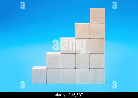 Stapel von hölzernen Spielzeugblöcken, die Treppen auf blauem Hintergrund isoliert machen. Konzept für das Wachstum von Unternehmen. Stockfoto