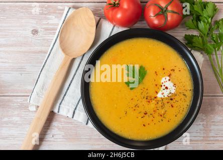 Rote Linsenpüree-Suppe auf einem Teller mit einem Holzlöffel. Blick von oben. Stockfoto