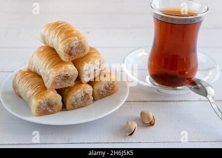 Traditionelles türkisches Gebäck, süßes Baklava-Dessert, auf einer Holzoberfläche mit türkischem Tee und Pistazien. Stockfoto