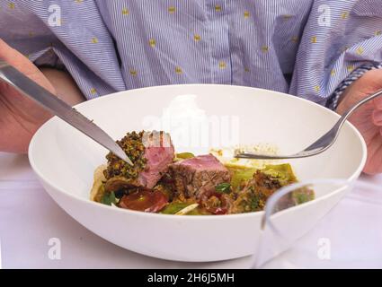 Blick von oben auf elegante Frauenhände, die Gabel und Messer über der Platte halten Stockfoto