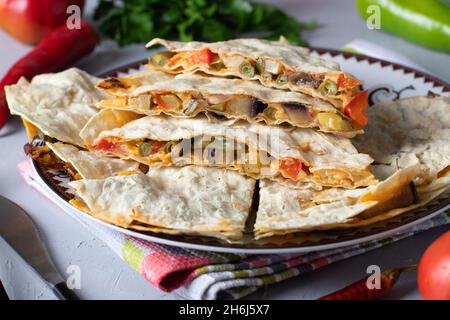 Mexikanische Tortilla Quesadilla Vorspeise mit Gemüse und Käse in Teller auf grauem Hintergrund Stockfoto