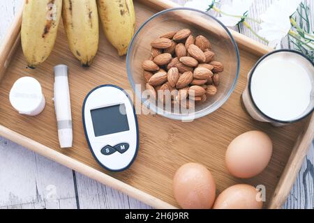 Messgeräte für Diabetiker, Banane, Ei und Milch auf einem Tisch Stockfoto