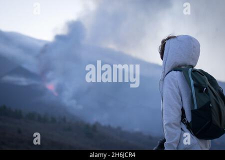 Tourist girl watching Cumbre Vieja vulkanischen Ausbruch auf der Insel La Palma, Kanarische Inseln. Vulkan La Palma von weitem. Stockfoto