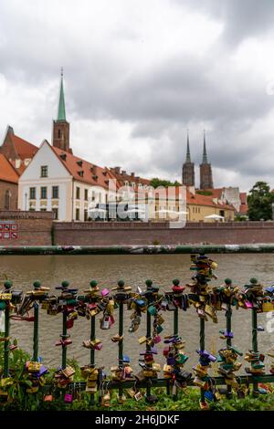 Breslau, Polen - 17. September 2021: Blick auf Liebesschlösser auf einem Brückengeländer in Breslau mit der Kathedrale im Hintergrund Stockfoto