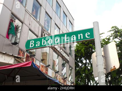 Ein grünes Straßenschild für die Baboo Lane mit dem Minora Center Gebäude im Hintergrund auf der Serangoon Road in Little India, Singapur. Stockfoto