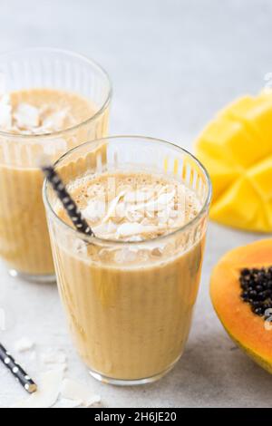 Vegan tropischer Smoothie aus Mango, Kokosnuss und Papaya im Glas, Nahaufnahme Stockfoto