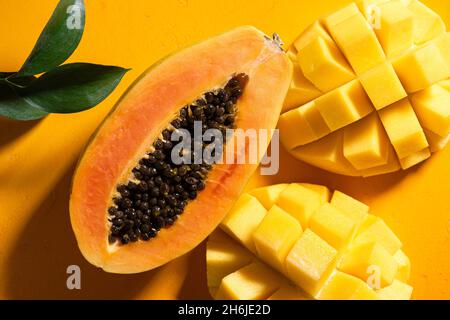 Papaya und Mango tropischen Früchte auf gelbem Hintergrund flach lag mit natürlichem Sonnenlicht und Schatten Stockfoto