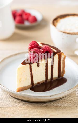 Käsekuchen mit Schokoladensauce und frischen Himbeeren auf dem Teller, Nahaufnahme Stockfoto