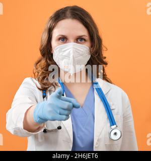 Ein Arzt in Uniform zeigt seinen Finger nach vorne auf Sie, Studiohintergrund Stockfoto