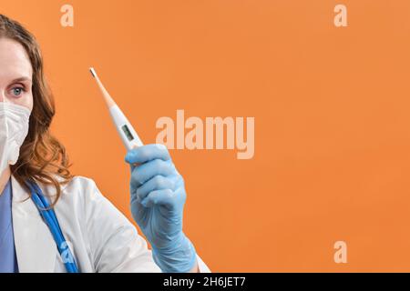 Eine Ärztin hält ein elektronisches Digitalthermometer in der Hand. Medizinisches Instrument zur Messung der Körpertemperatur, Studio-Hintergrund Stockfoto