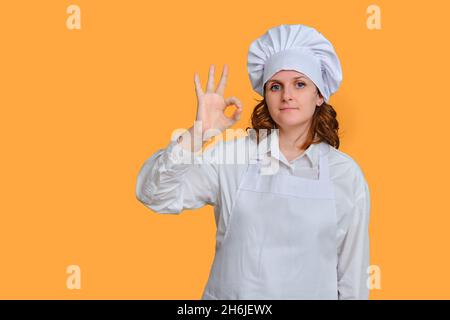 Die Chefin lächelte und zeigte eine gute Geste auf gelbem Studiohintergrund, Kopierraum Stockfoto