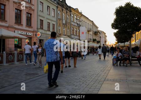 Lublin, Polen - 10. September 2021: In der Abenddämmerung spazieren die Menschen entlang der breiten Promenade, die zwischen Mietshäusern verläuft. Stockfoto