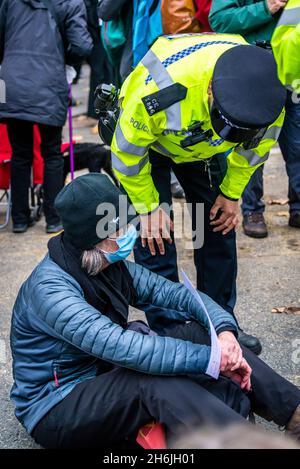 Polizei, die sich mit einem Protestierenden einlässt, der sich weigert, sich von der Straße zu bewegen, Rise and Rebel march, Extinction Rebellion, London, Großbritannien. November 2021 Stockfoto