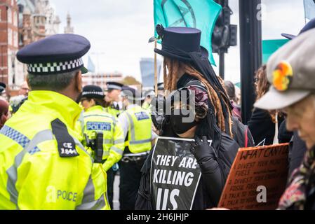 Schwarz gekleidete Frau mit Plakat „Sie töten uns“ während des Protestes gegen Lord Mayor Show, Rise and Rebel march, Extinction Rebellion, London, Großbritannien. November 2021 Stockfoto