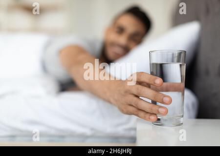 Junger Arabischer Mann Nimmt Morgens Ein Glas Wasser Vom Nachttisch Stockfoto