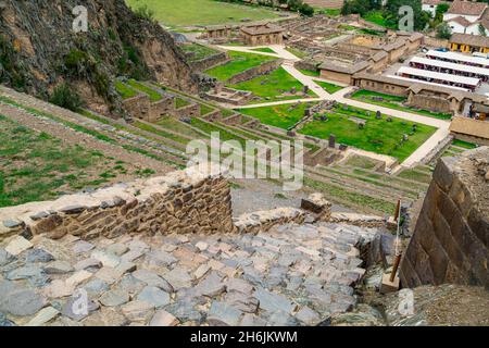 Blick auf die Terrassen von Pumatallis in der archäologischen Stätte der Inka und auf den Souvenirmarkt in Ollantaytambo, Peru. Stockfoto